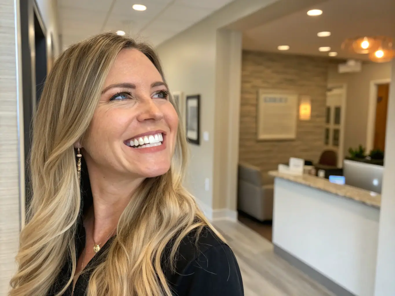 A patient smiling in a modern dental clinic in Cyprus, with a doctor in the background.